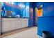 Bathroom with a double vanity, a large mirror, blue walls, and orange accent colors in an adjacent room at 136 Durie Way, Garner, NC 27529