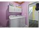 Well-lit laundry room featuring white cabinets and modern washer and dryer units at 136 Durie Way, Garner, NC 27529