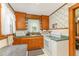 Functional kitchen featuring wooden cabinets, white appliances, green countertops, and floral wallpaper at 2129 Wrenn St, Burlington, NC 27215