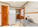 View of the kitchen featuring white appliances, wooden cabinets, and floral wallpaper at 2129 Wrenn St, Burlington, NC 27215