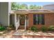 Charming brick home featuring a covered front entrance with white railing and updated black front door at 232 Clancy Cir, Cary, NC 27511