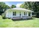 This well-maintained home features a covered front porch, white siding, and green shutters, set on a lot with mature trees at 310 Spring St, Durham, NC 27703