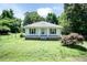 Charming single-story home featuring a covered front porch, white siding, neatly trimmed shutters, and a spacious front yard at 310 Spring St, Durham, NC 27703