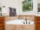 Close up of the tub area in a bathroom showing the tiled surround and large window with a view of trees at 3581 Boulder Ct, Wake Forest, NC 27587