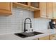 Kitchen sink with modern stainless steel appliances, bright subway tile backsplash and wood cabinets at 4404 Oak Park Rd, Raleigh, NC 27612