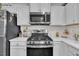A stainless steel oven and microwave complement the white cabinets and quartz countertops in this kitchen at 48 Highview Ct, Fuquay Varina, NC 27526