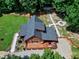 Aerial view of a log cabin showing deck, outbuilding, stone firepit, and lush green lawn at 52 Buoy Dr, Henderson, NC 27537