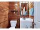 Cozy bathroom featuring wood paneled walls, a vanity with a mirror, and a modern toilet at 52 Buoy Dr, Henderson, NC 27537