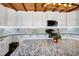A granite island in the kitchen provides a focal point amid white cabinets and a rustic wood ceiling at 52 Buoy Dr, Henderson, NC 27537