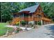 Log home exterior featuring a sprawling deck, tall windows, and mature trees at 52 Buoy Dr, Henderson, NC 27537