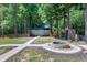 Tranquil backyard featuring a shed, fire pit, mature trees, and stone pathways at 52 Buoy Dr, Henderson, NC 27537