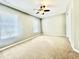 Bright bedroom featuring a ceiling fan, two large windows, and neutral carpet at 5419 Vista View Ct, Raleigh, NC 27612
