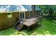 View of the rear of the brick home with a well-maintained wooden deck and stairs at 7194 Johns Point Ct, Liberty, NC 27298