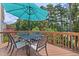 Outdoor deck featuring a dining table with seating, shade umbrella, and view of backyard trees at 8106 Sommerwell St, Raleigh, NC 27613