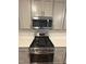 Stainless steel oven beneath gray cabinets and a gray microwave at 0416 Hazy Hls Ln, Garner, NC 27529