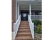 Brick home with a welcoming front porch, stairs, and elegant security features at 1126 Woodlands Creek Way, Apex, NC 27502