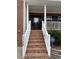 A close-up of the front porch with brick stairs, a black front door, and white pillars at 1126 Woodlands Creek Way, Apex, NC 27502
