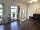 Airy room featuring dark wood floors, lots of plants, a grandfather clock, and a white front door at 1126 Woodlands Creek Way, Apex, NC 27502