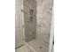 Newly renovated shower featuring marble tiles and convenient built-in shelving at 1126 Woodlands Creek Way, Apex, NC 27502