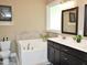 Luxurious bathroom with a soaking tub, double vanity, tile accents, and a bright window at 120 Glen Oaks Dr, Youngsville, NC 27596