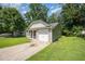 View of the backyard with green grass and a detached single car garage with driveway at 125 Brook Pl, Smithfield, NC 27577