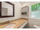Bathroom with granite countertop, a dark-framed mirror, gray cabinet, and a window for natural light at 1317 Elmset Ln, Durham, NC 27713