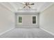 Expansive main bedroom with neutral carpet, tray ceiling, and natural light from dual windows at 157 Cherrybirch Ln, Zebulon, NC 27597