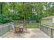 View of the wood back deck with chairs and table, overlooking a playground area in the yard at 1704 Little John Ct, Burlington, NC 27217