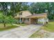 Two-story home with yellow siding, brick accents, a covered carport, and a long driveway at 1704 Little John Ct, Burlington, NC 27217