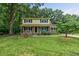 Charming two-story home with a brick and yellow exterior, a covered front porch, and a green lawn at 1704 Little John Ct, Burlington, NC 27217