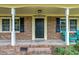 Close up of front porch with brick columns, blue chairs, and a black front door at 1704 Little John Ct, Burlington, NC 27217
