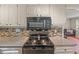 Close-up of kitchen with stainless steel stove and microwave, mosaic backsplash, and granite countertops at 1704 Little John Ct, Burlington, NC 27217