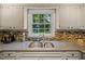 Bright kitchen featuring a stainless steel sink, granite countertops, mosaic backsplash, and backyard view at 1704 Little John Ct, Burlington, NC 27217