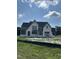 Exterior of new construction home with stone facade, gray trim, and ample windows under a partly cloudy sky at 200 Meadow Walk Dr, Fuquay Varina, NC 27526