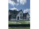 New home exterior showcasing stone details, gray trim, and an abundance of natural light through black windows at 200 Meadow Walk Dr, Fuquay Varina, NC 27526