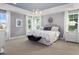 Spacious primary bedroom featuring large windows, tray ceiling, decorative lighting, and plush carpeting at 219 Faith Avenue, Sanford, NC 27330