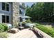 Stone exterior home with a spacious deck including a hot tub, lounge chairs, and a peaceful, shady backyard at 267 Bald Eagle Dr, Pittsboro, NC 27312