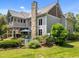 Back exterior of the home with a stone chimney, large deck, hot tub, and lush landscaping, ideal for outdoor living at 267 Bald Eagle Dr, Pittsboro, NC 27312