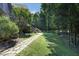 Stone pathway leading through a lush backyard, surrounded by mature trees and vibrant green grass at 267 Bald Eagle Dr, Pittsboro, NC 27312