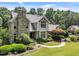 An elevated view of a well-maintained home with stone accents, lush greenery, and a circular driveway at 267 Bald Eagle Dr, Pittsboro, NC 27312