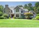 Beautiful two-story home featuring a stone chimney, large windows, a manicured lawn, and mature landscaping at 267 Bald Eagle Dr, Pittsboro, NC 27312