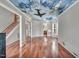 Bright, open living space featuring hardwood floors and a custom ceiling mural, leading to the staircase at 3212 Marblewood Ct, Raleigh, NC 27604