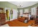 A green-walled bedroom featuring wooden floors, a queen bed, a chandelier, and closet space at 401 N Main St, Louisburg, NC 27549
