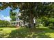 View of a two-story white home with a welcoming front porch, partially shaded by a large magnolia tree at 401 N Main St, Louisburg, NC 27549