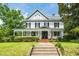 Charming two-story home with black shutters and a welcoming front porch, framed by lush greenery at 401 N Main St, Louisburg, NC 27549