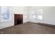 Well-lit living room with a brick fireplace, large windows, and wall mounted baseboard heating at 402 Poplar St, Graham, NC 27253