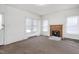 Bright living room featuring a brick fireplace, large windows, and carpeted flooring in need of repair at 402 Poplar St, Graham, NC 27253