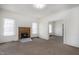 Spacious living room with a brick fireplace, carpeted floors, and ample natural light from large windows at 402 Poplar St, Graham, NC 27253