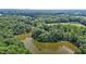 Aerial view of a wooded property with a lake and a house surrounded by trees at 4070 Swannie Coble Rd, Snow Camp, NC 27349