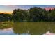 Scenic lake view surrounded by lush greenery, reflecting a tranquil sunset sky at 4070 Swannie Coble Rd, Snow Camp, NC 27349